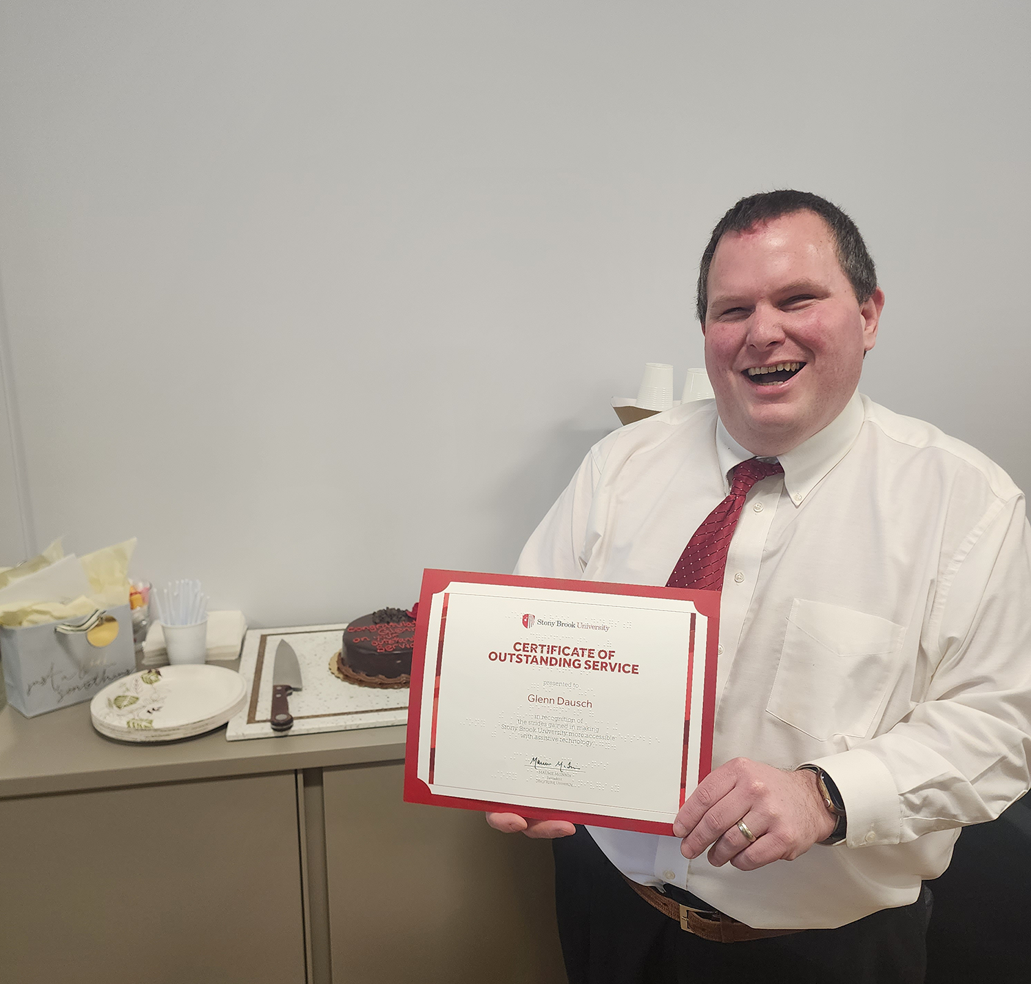 Glenn Dausch shows off his award next to a celebatory cake