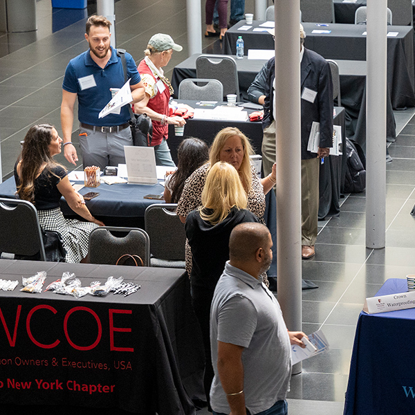 image of a vendor fair with tables set up from different companies and folks talking at those tables